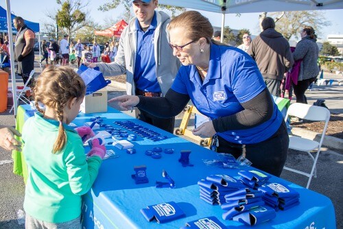Atlantic Self Storage employee at a booth at the Thin Mint 5k talks to a child